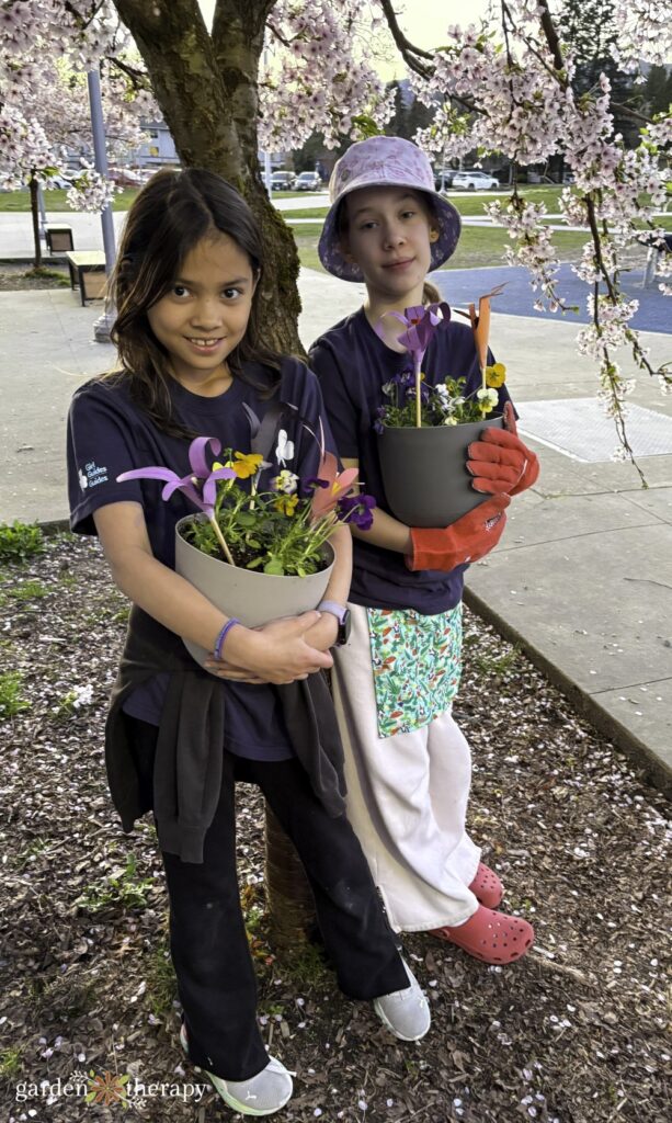Girl Guides outside with cherry blossom tree posing with their lily bulb planters