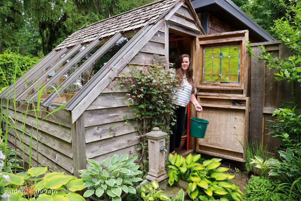 Stephanie posing in front of a wooden potting shed holding a green bucket