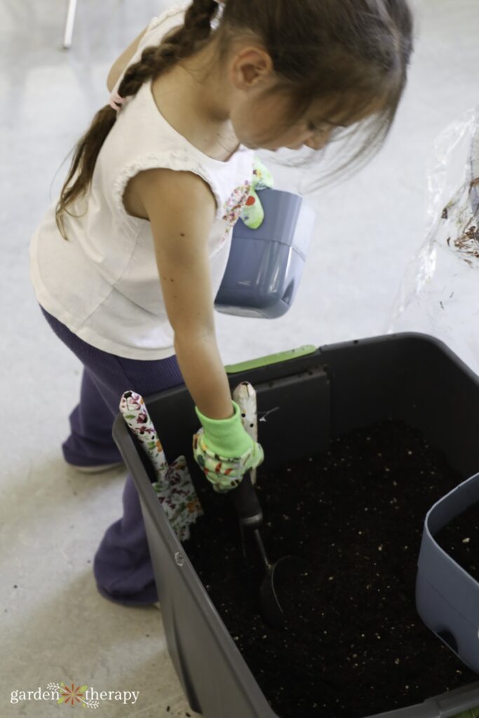 young girl filling pot with potting soil