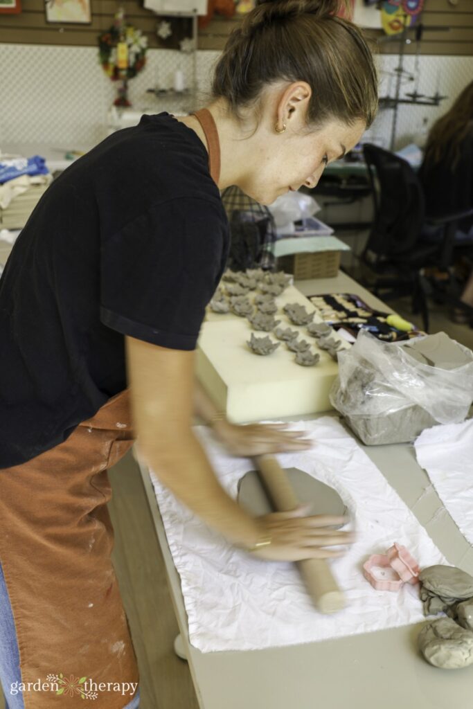 woman rolling out clay with rolling pin