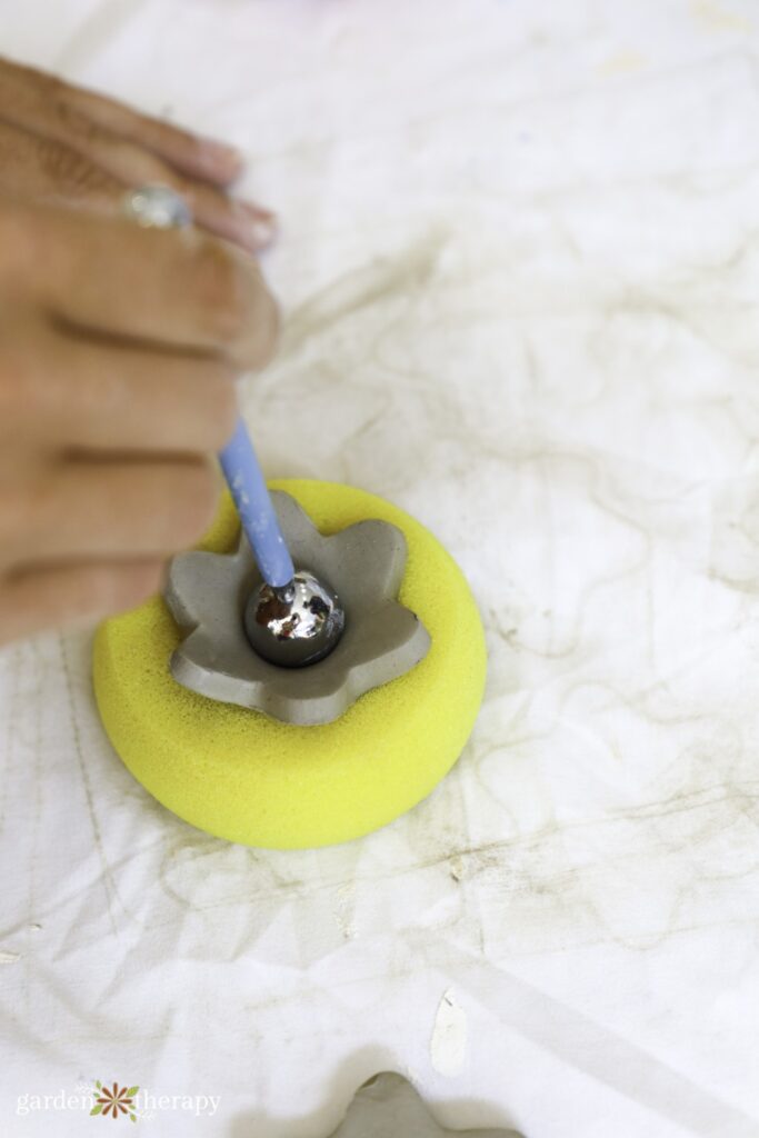 pressing clay flower into pottery sponge